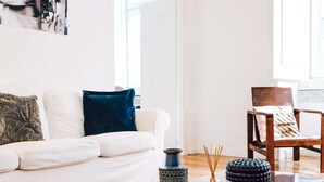 Una sala de estar moderna con un sofá blanco, una mesa de centro de vidrio y una alfombra colorida.