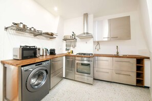 Eine kompakte Küche mit Waschmaschine, Mikrowelle, Herd, Backofen und Edelstahl-Schränken.
