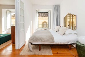 A bedroom with a bed, a window, a balcony, and a wall-mounted mirror. - Cheese&Wine™ | Alfama - Sé Cathedral 2 (Lisboa)