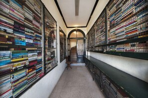 A library with bookshelves on both sides of a central staircase. - Cheese&Wine™ | Chiado - Rossio Square 1 (Lisboa)