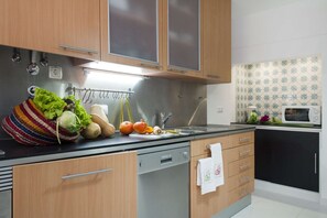 A modern kitchen with wooden cabinets, a stainless steel sink, and a microwave. - Cheese&Wine™ | Chiado - Rossio Square 1 (Lisboa)