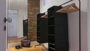 Ein Korridor mit Holzboden, einem Spiegel, einem schwarzen Kleiderständer und einem schwarzen Regalelement.