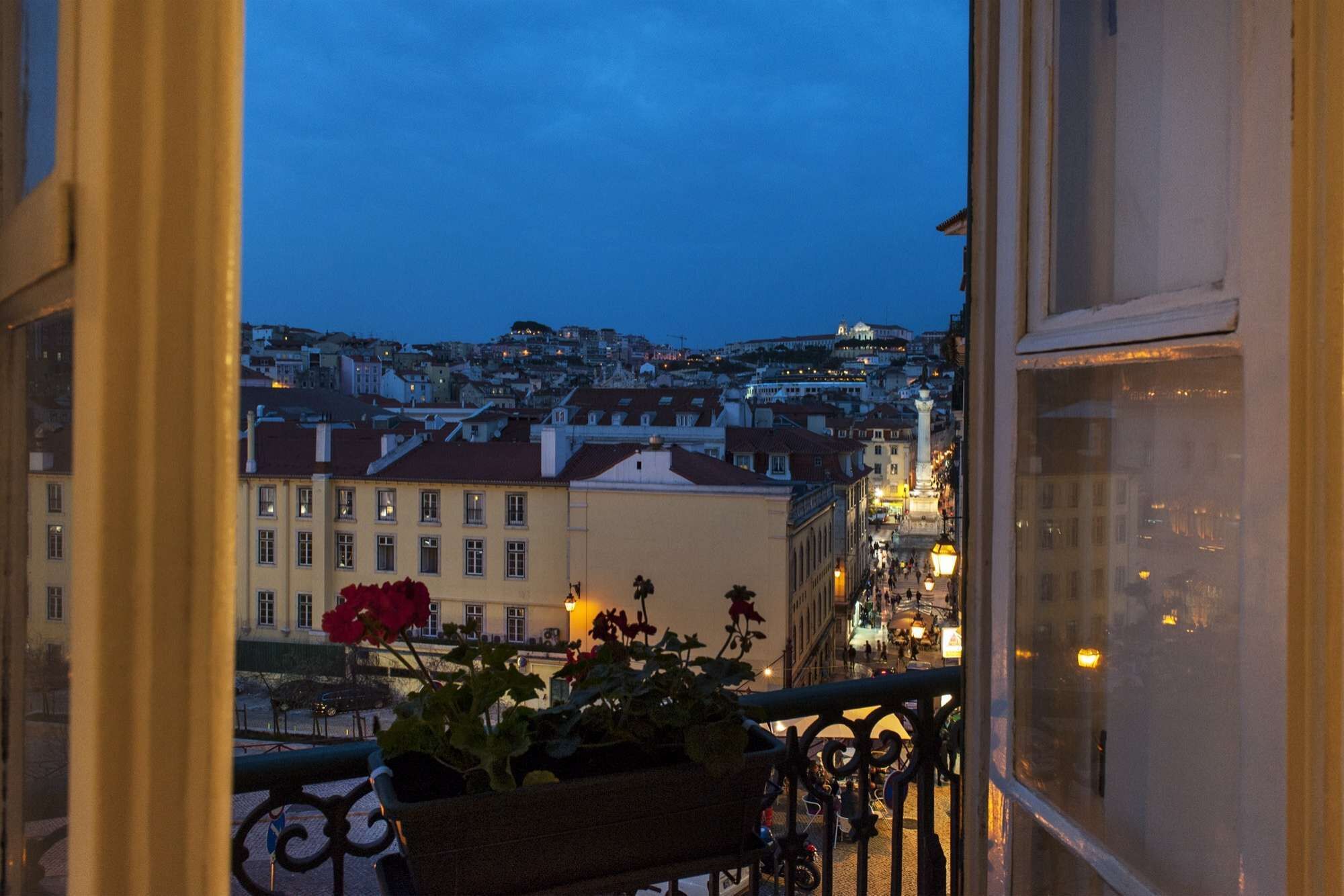 A balcony with a view of a cityscape at dusk, including buildings and a hill in the background.