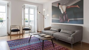 A living room with a sofa, two chairs, a coffee table, and a large painting on the wall. - Cheese&Wine™ | Chiado - Rossio Square 2 (Lisboa)