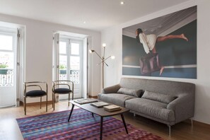 Ein Wohnzimmer mit einer Couch, zwei Sesseln, einem Couchtisch und einem großen Gemälde an der Wand.