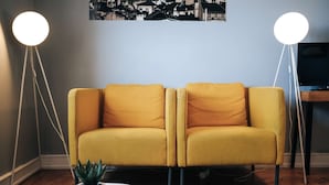 A living room with a sofa, two floor lamps, a small table with a plant, and a television. - Cheese&Wine™ | Sra. do Monte - Viewpoint 3 (Lisboa)
