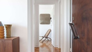 Ein Korridor mit Holzboden, einem Sessel, einer Wanddekoration mit Muster und einer Tür mit Griff.