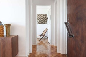 Ein Korridor mit Holzboden, einem Sessel, einer Wanddekoration mit Muster und einer Tür mit Griff.