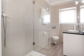 Ein modernes Badezimmer mit einer gläsernen Duschkabine, einer Toilette und einem Waschbecken mit Spiegel.