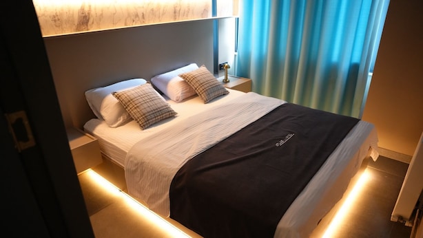 A modern hotel room with a neatly made bed, a bedside table, and a nightstand. - Atlas Suit Otel (mersin)