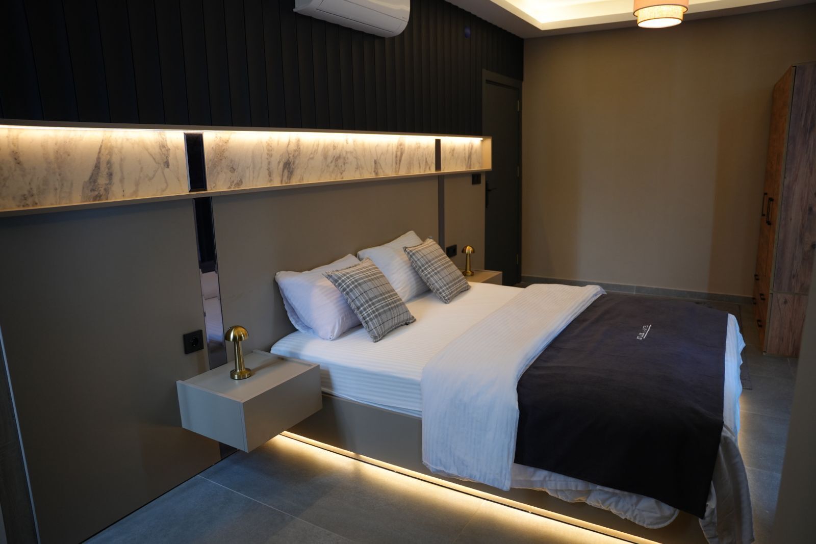 Un dormitorio moderno con cama, mesitas de noche y una lámpara de pared.