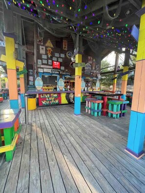 A wooden deck with colorful seating and a sign that reads 'LIVE THE LIFE YOU LOVE.' - Walk to Singleton Beach | Pools + Hot Tub (Hilton Head Island)