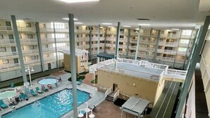 Piscina interna com espreguiçadeiras, solário e vista do interior do edifício.