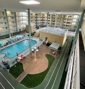 An indoor swimming pool with lounge chairs, a sun deck, and a view of the building's interior. - Walk to Singleton Beach | Pools + Hot Tub (Hilton Head Island)