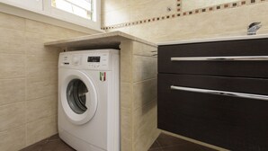 A compact laundry area with a washing machine, a dark cabinet, and tiled walls. - Bernini Alle Fornaci - St Peter Vatican (Rome)