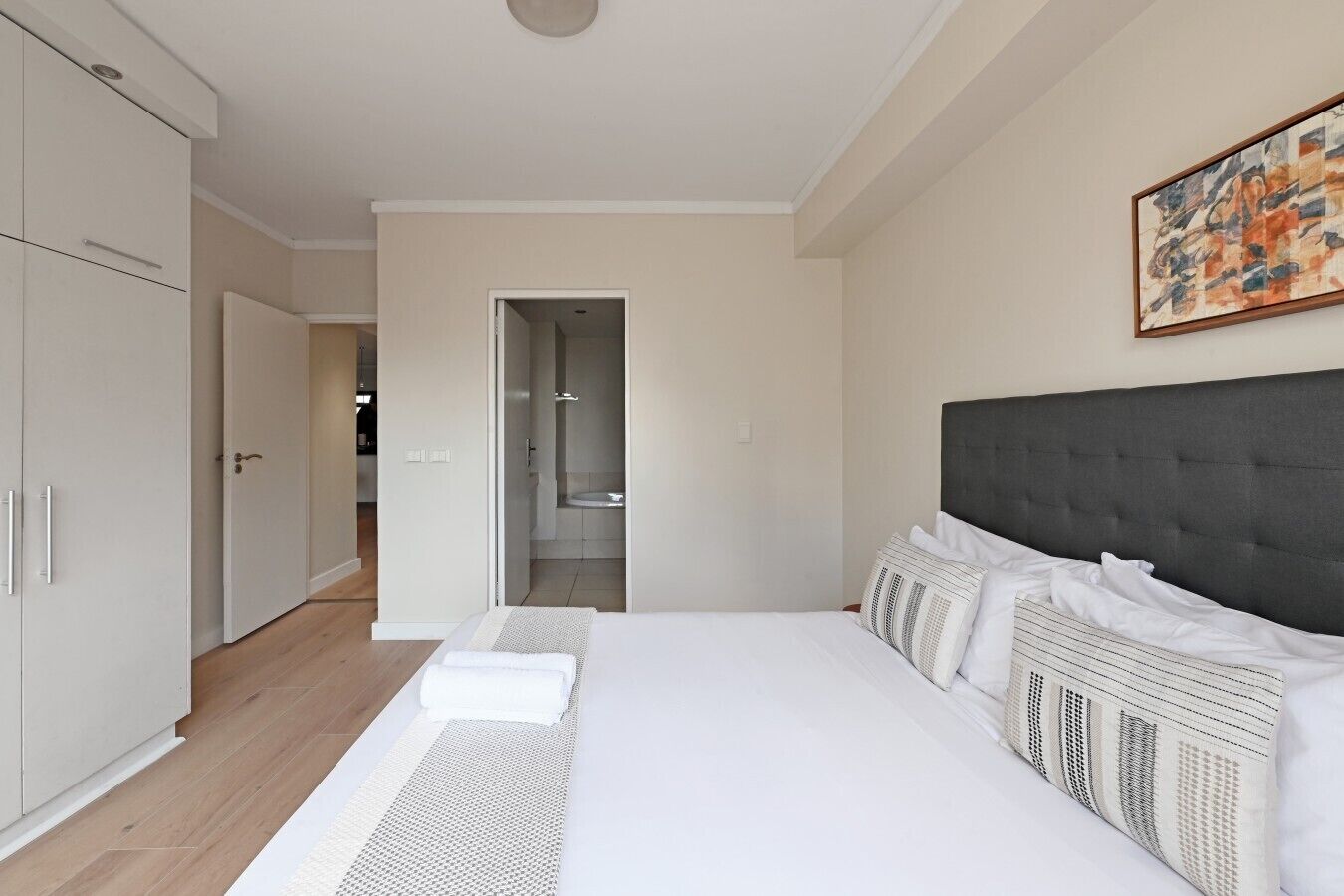 A bedroom with a large bed, a wardrobe, and a bathroom visible through an open door.