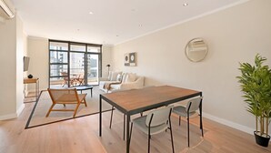 Una sala de estar moderna con comedor, ventanas amplias y una planta en maceta.