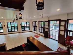 A spacious room with large windows, a wooden bench, and a ceiling fan. - Le Zaina's Fort Hotel (Kochi)