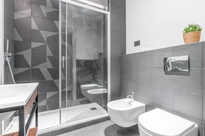 Ein modernes Badezimmer mit Duschkabine aus Glas, Waschbecken, Bidet und Toilette.