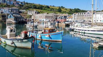 A harbor with boats docked, buildings in the background, and a clear sky.