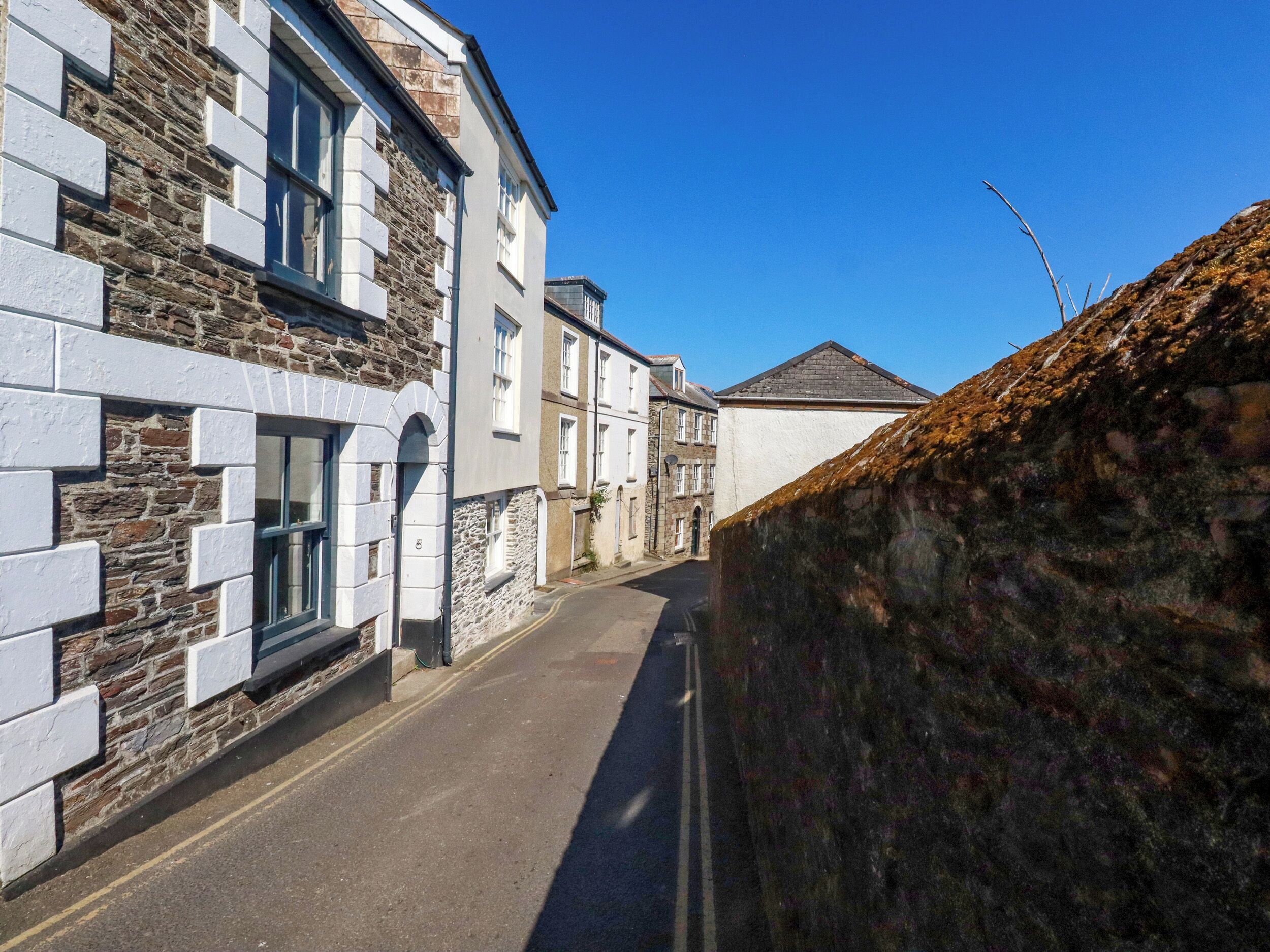 A narrow street with stone buildings, one with a visible window and door.