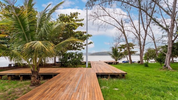 A wooden deck leading to a beach with palm trees and a view of the sea. - Casa c Churrasqueira a 400m da Praia de Barra Nova (Saquarema)