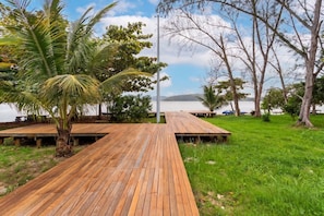 Um deck de madeira que leva a uma praia com palmeiras e vista para o mar.