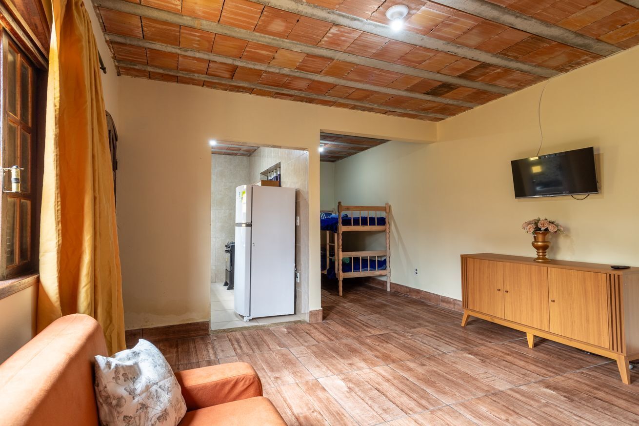 Una habitación con techo de madera, televisor montado en la pared, un armario de madera y una cama litera.