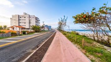 Uma estrada costeira com calçada, edifícios e uma praia ao longe.