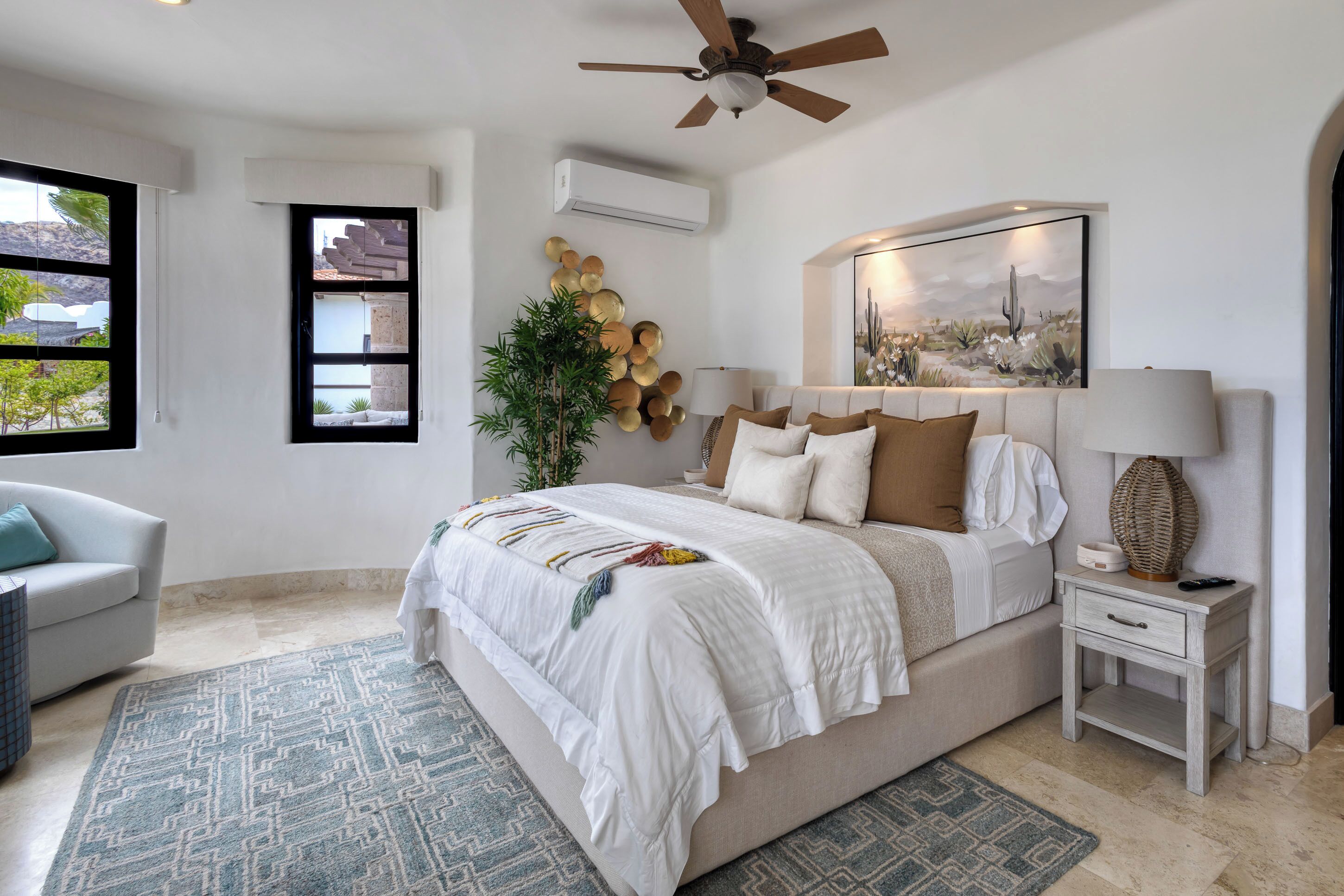 A bedroom with a bed, a nightstand, a lamp, a ceiling fan, a window, and a wall-mounted air conditioner.