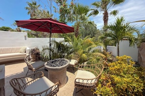 An outdoor seating area with wicker chairs, a round table, and a red umbrella. - Hillside Costa Azul Villa with Pool, Hot Tub & Ocean Views (San Jose del Cabo)
