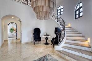 A spacious foyer with a grand staircase, a round table, and two chairs. - Hillside Costa Azul Villa with Pool, Hot Tub & Ocean Views (San Jose del Cabo)