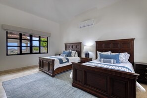 Ein Schlafzimmer mit zwei Holzbett, einem großen Fenster und einer Klimaanlage.