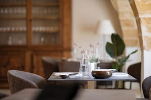 A dining table set with clear glassware, a bowl, and a vase with flowers.