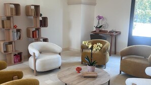Uma sala de estar moderna com uma mesa de centro redonda, duas poltronas, um sofá e uma estante.