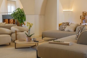 A modern living room with a sofa, armchairs, a coffee table, and a large plant.