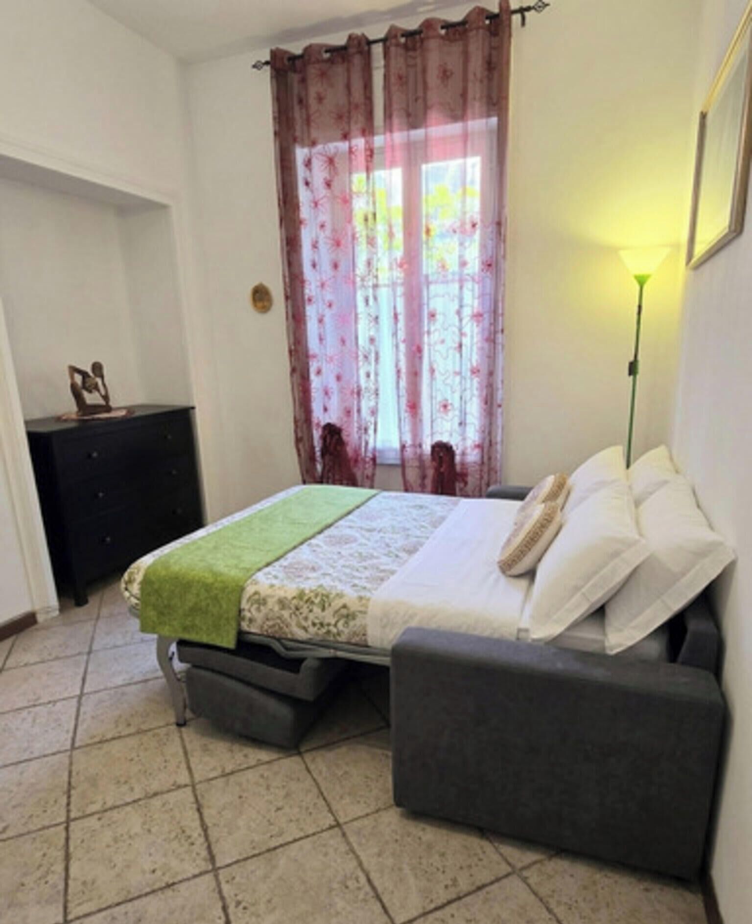 Quarto com cama, mesa de cabeceira e abajur.