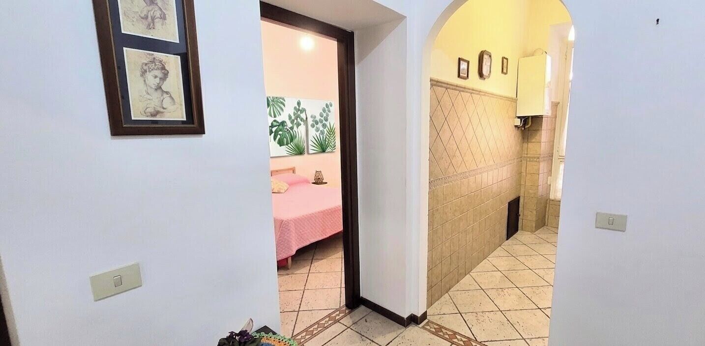 A hallway with a bed, a door, and a tiled wall.