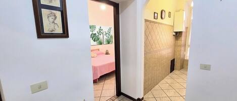 A hallway with a bed, a door, and a tiled wall.