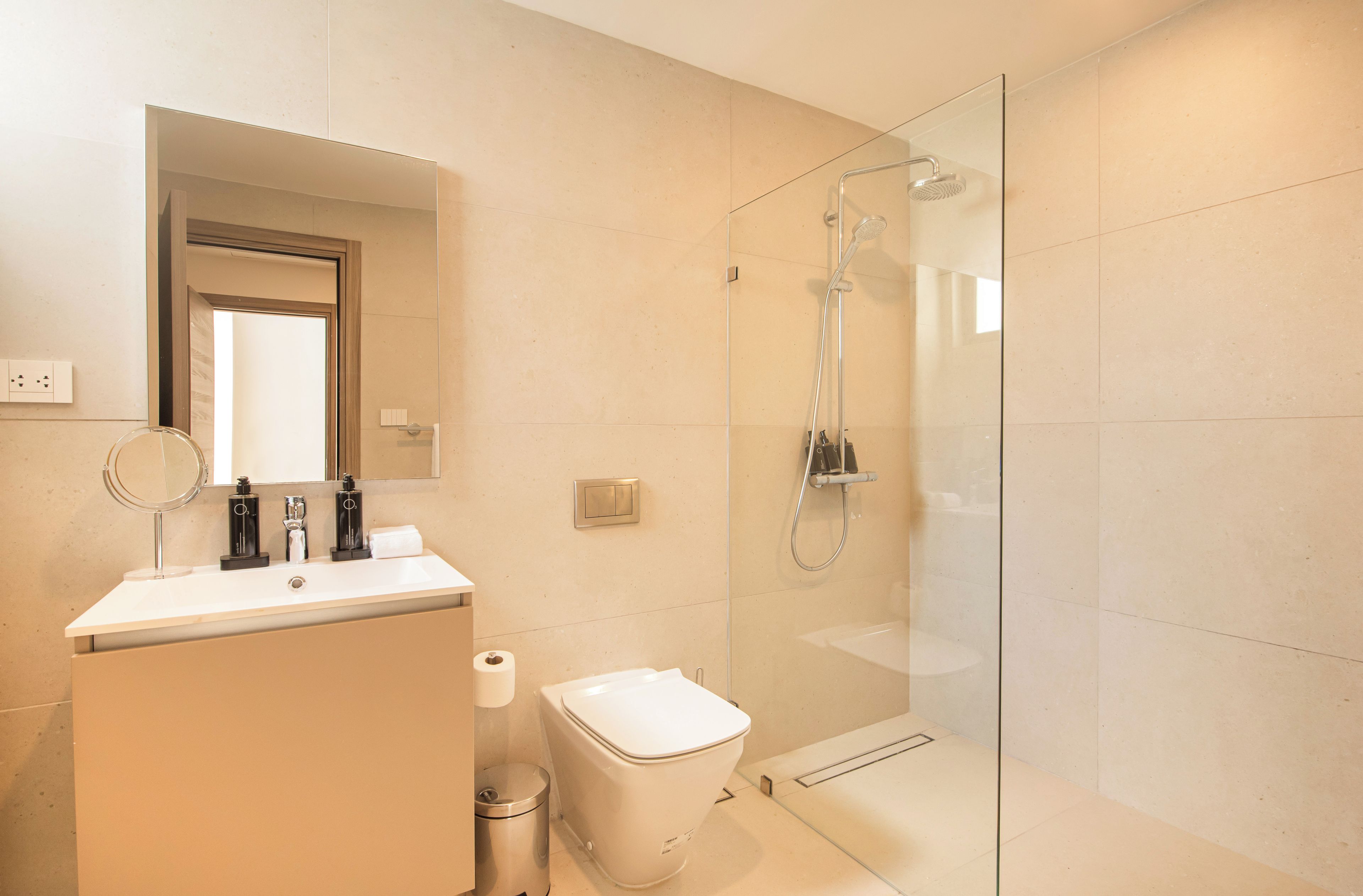 A modern bathroom with a glass-enclosed shower, a white sink, and a mirror.