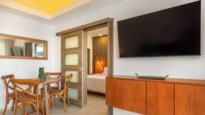 Hotellihuone, jossa on ruokailutila, sänky, televisio ja kaappi.