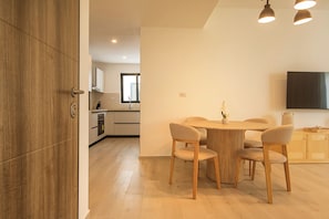 A modern kitchen with a dining area, wooden flooring, and a flat-screen TV mounted on the wall. - Nivia Punta Cana Hotel & Residences (Punta Cana)