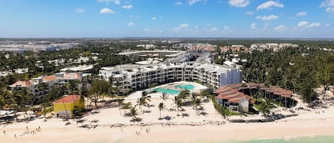 A resort with a central pool, beachfront, and multiple buildings.