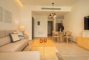 A modern living room with a sofa, coffee table, and dining area. - Nivia Punta Cana Hotel & Residences (Punta Cana)