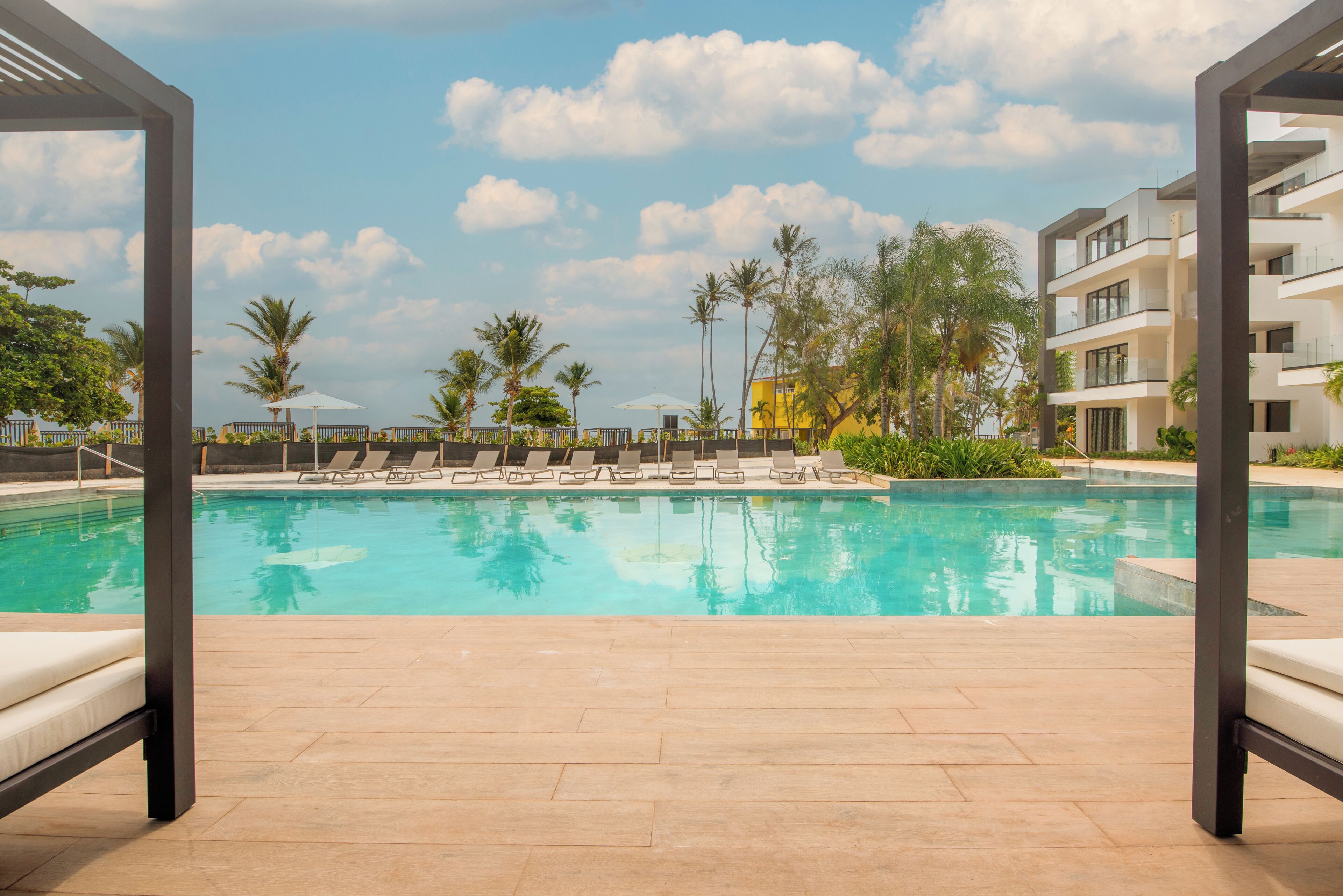 Uma área de piscina com espreguiçadeiras e um céu ensolarado.