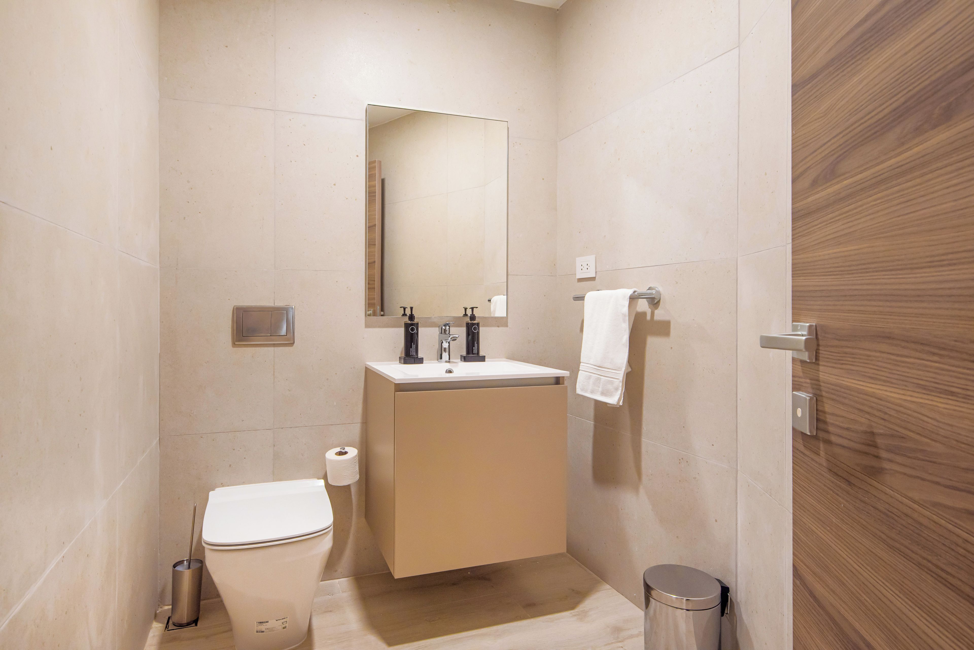 Een badkamer met toilet, wastafel, spiegel en een handdoekrek.