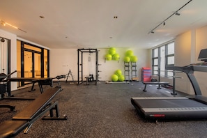 A gym with exercise equipment, treadmills, and a wall-mounted squat rack. - Nivia Punta Cana Hotel & Residences (Punta Cana)