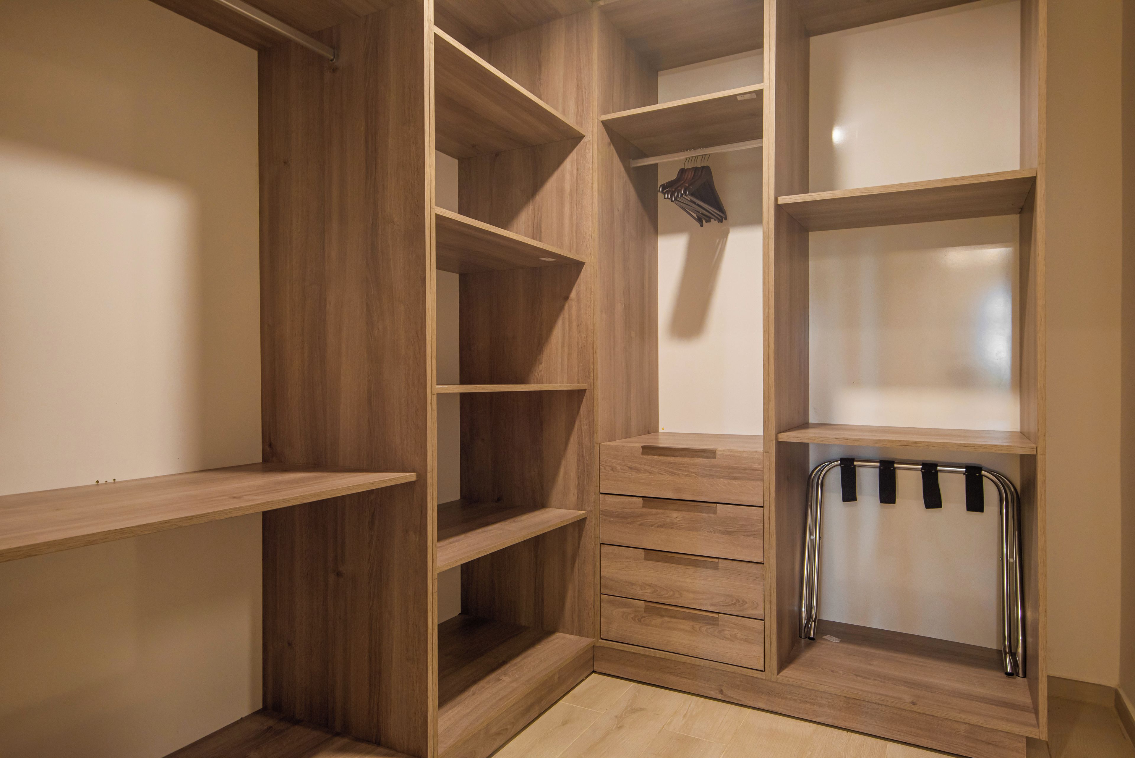 Ein begehbarer Kleiderschrank mit mehreren Holzböden und Schubladen.