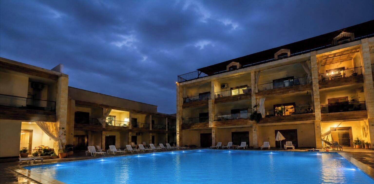 A multi-story hotel with a swimming pool, balconies, and outdoor seating areas.