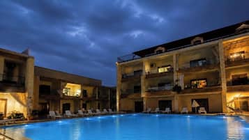 A multi-story hotel with a swimming pool, balconies, and outdoor seating areas.
